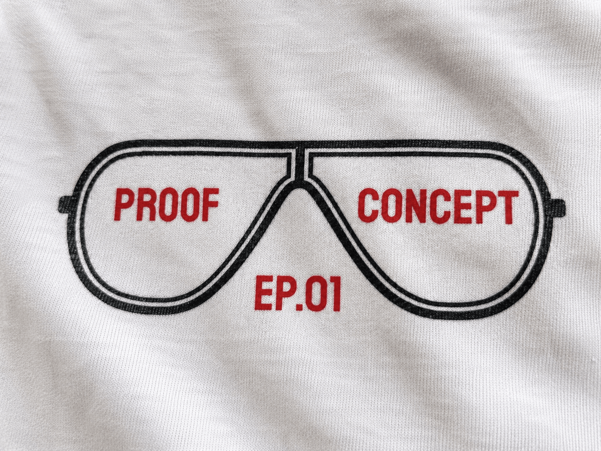 A close-up of a white fabric surface featuring a graphic of aviator-style glasses outlined in black, with the words 'PROOF' and 'CONCEPT' in red inside the lenses and 'EP.01' in red below.