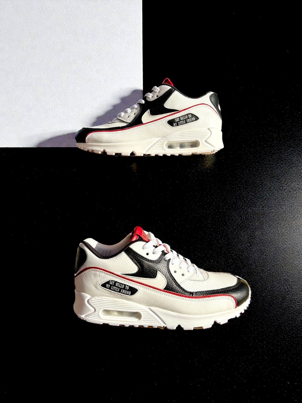 A pair of Nike Air Max 90 sneakers in white, black, and red - Scarface
